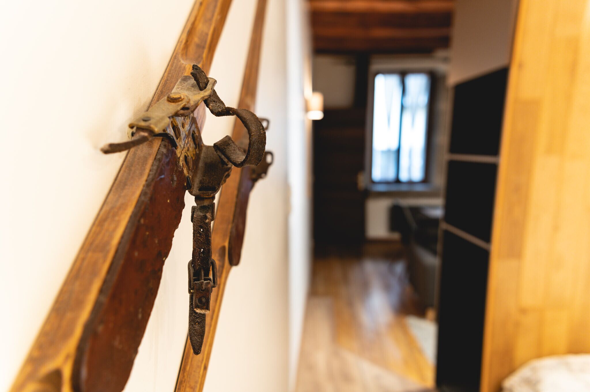 Letto con struttura in legno e dettagli in metallo, pavimento di legno e una finestra sullo sfondo.