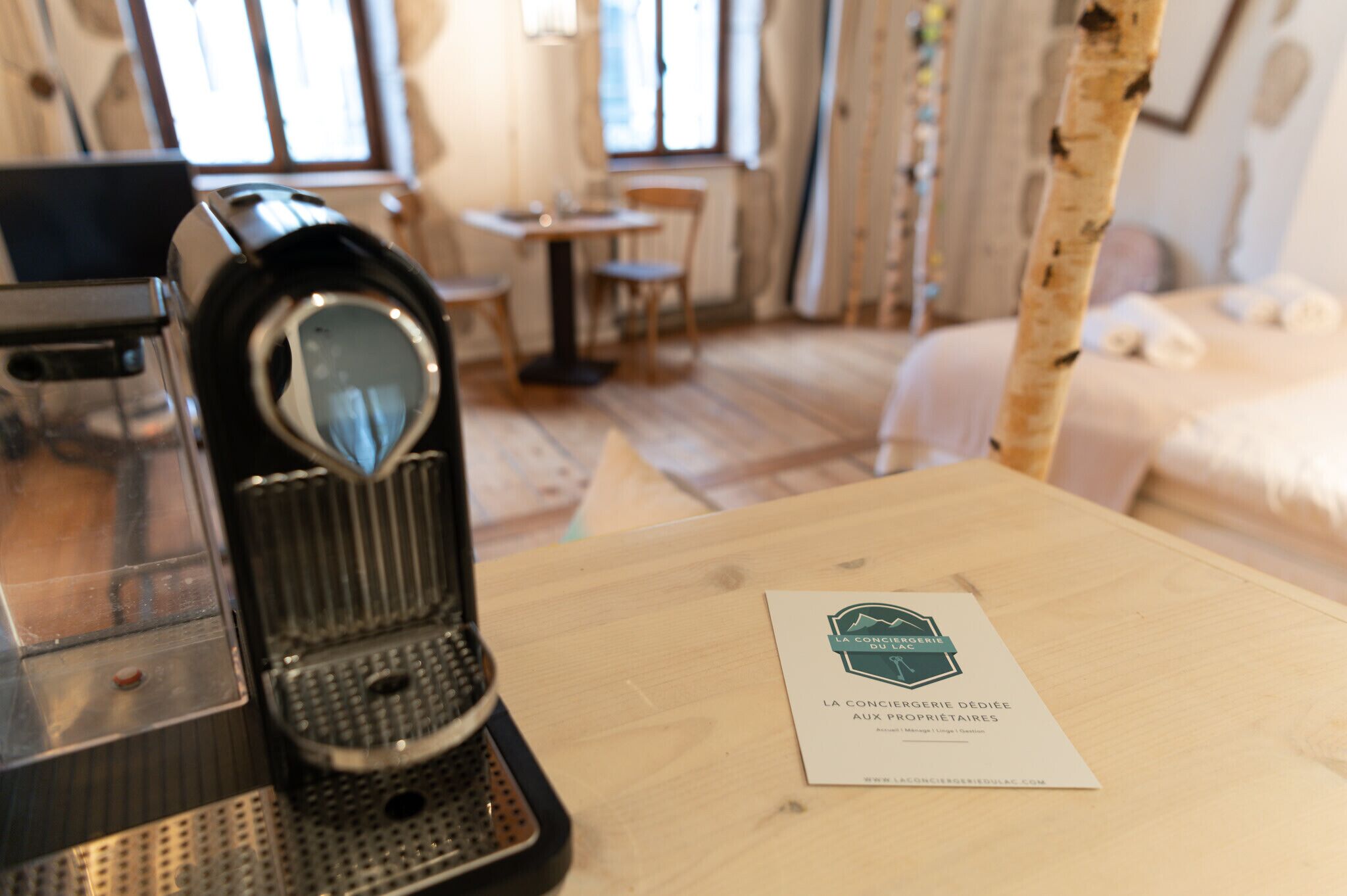 A wooden table with a coffee machine and a business card.