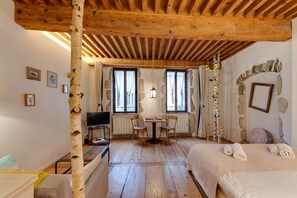 A cozy room with a wooden ceiling, a stone wall, a bed with towels, a table with chairs, and a TV. - La Cour Filaterie - Suite of 30 sq. m in the ❤️ Annecy 🥐 breakfast included (Annecy)