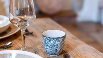 Une table en bois avec une assiette, un verre, une tasse à motifs et une cuillère.
