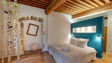 A bedroom with a wooden ceiling, a stone wall, a bed with white bedding, and a blue accent wall.