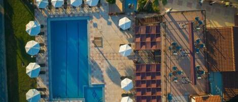 An aerial view of a swimming pool area with multiple sun umbrellas and seating arrangements.