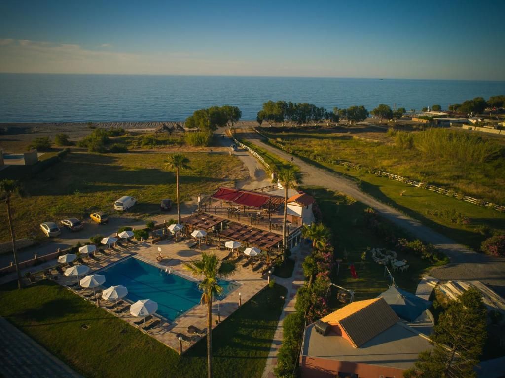 A resort with a swimming pool, outdoor seating, and a view of the sea.