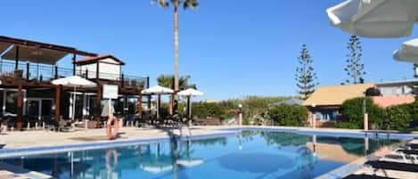 Una piscina al aire libre de temporada, sombrillas