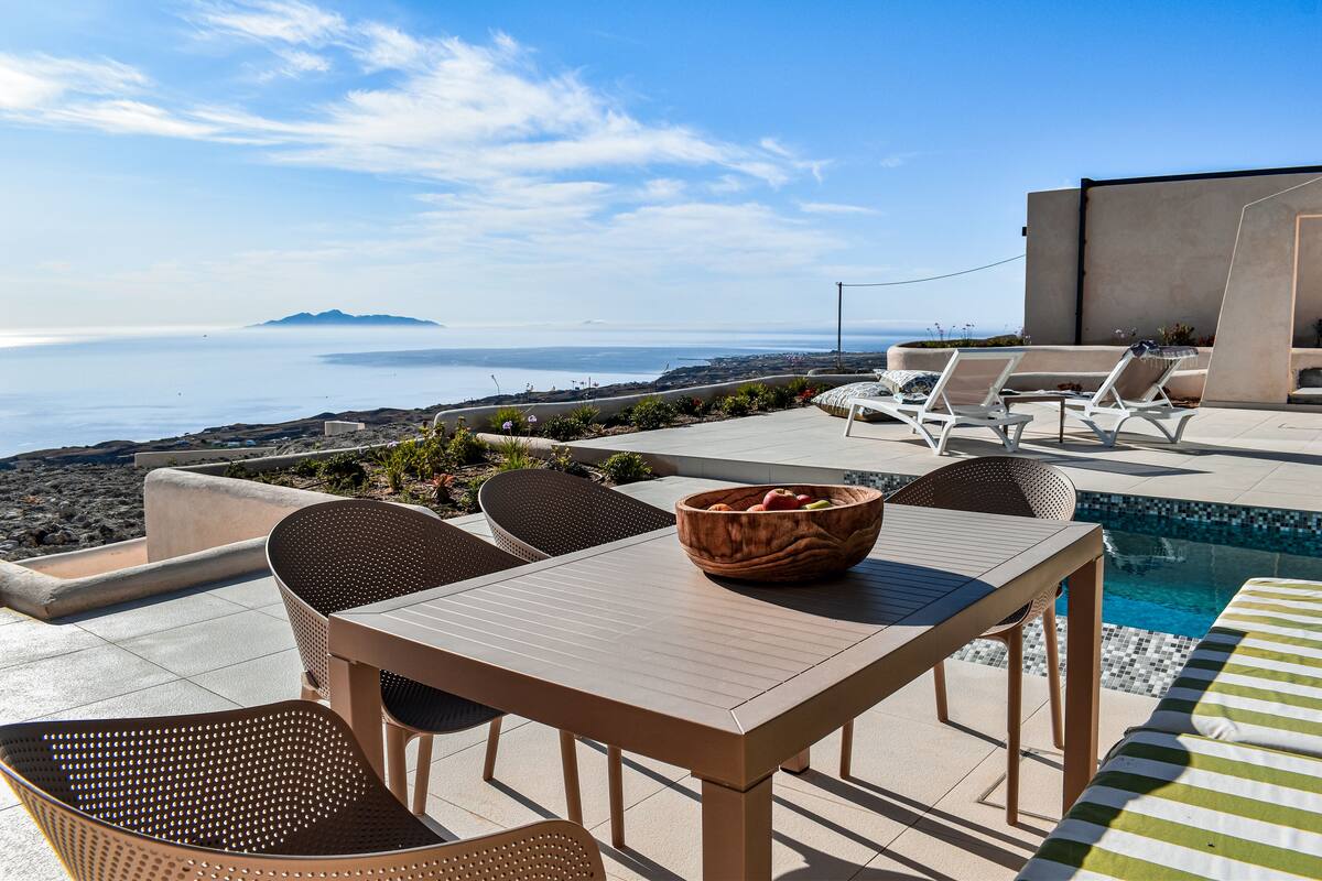 A terrace with a pool, lounge chairs, and a table with a fruit bowl.