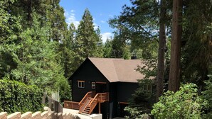 A lodge with a staircase leading to a wooden deck, surrounded by dense forest.