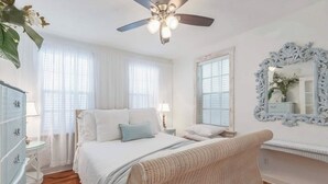 Un dormitorio con cama, ventilador de techo, cómoda y espejo.