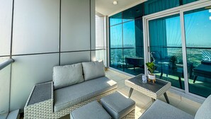 A balcony with a sofa, a small table, and chairs. - HiGuests - The Marina Torch (Dubai)