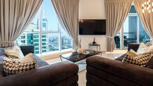 A modern living room with a large window, a flat-screen TV, and a sofa with patterned cushions. - HiGuests - The Marina Torch (Dubai)