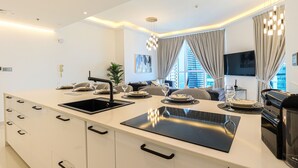 A modern kitchen with a black countertop, white cabinetry, and a built-in stove. - HiGuests - The Marina Torch (Dubai)