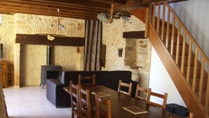 Un comedor con mesa y sillas de madera, un sofá y una pared de piedra.