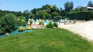 Un área de piscina con sillas de descanso, una playa de arena y un césped.