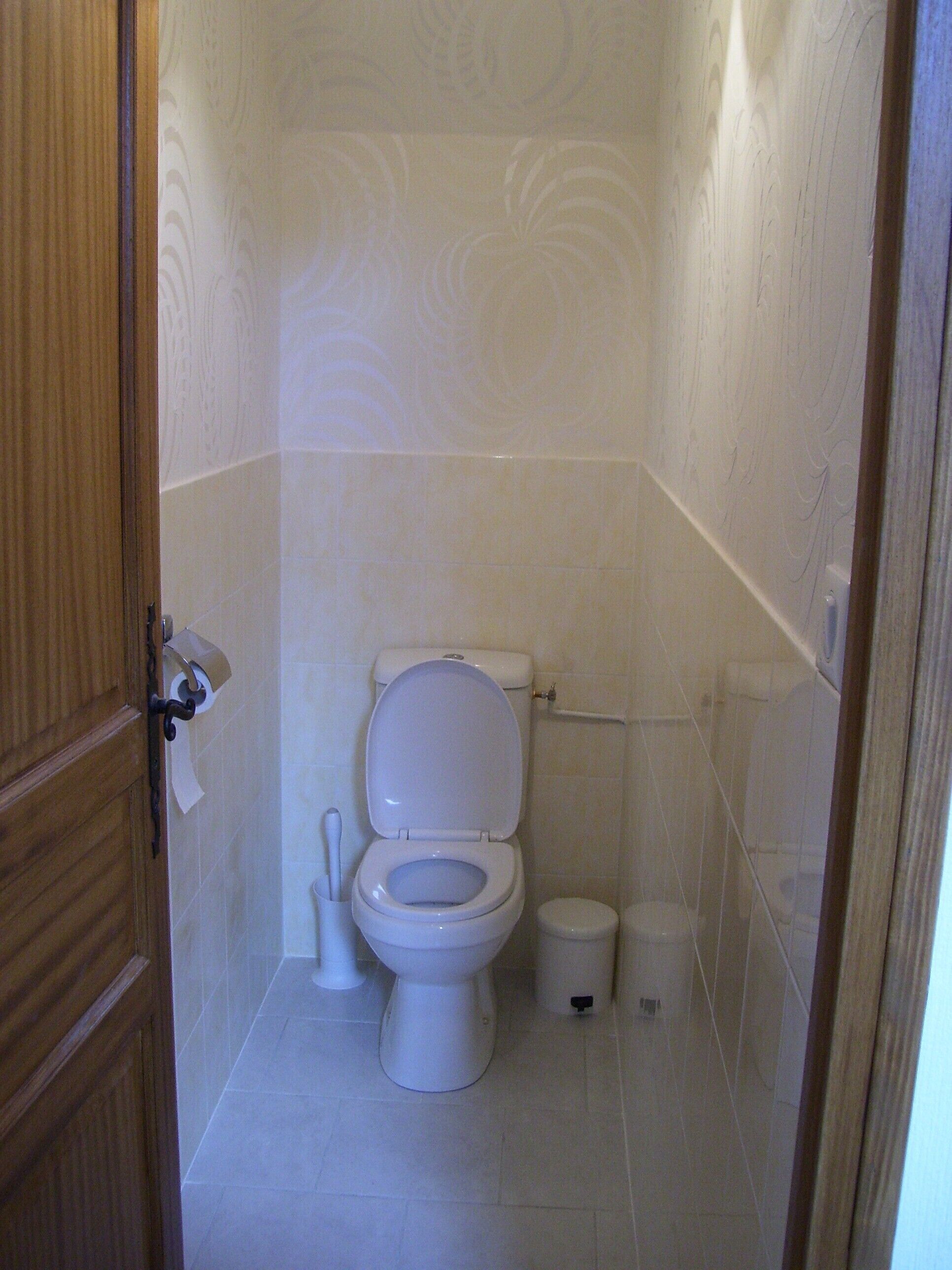 Un baño pequeño y blanco con inodoro, bidé y cubo de basura.