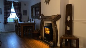 Ein gemütliches Zimmer mit Kamin, Holzmöbeln und einem Fenster mit Karottenvorhängen.