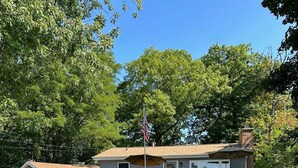 A two-story house with a front deck, a flagpole, and a chimney.