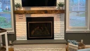 A living room with a fireplace, a mounted TV, and a blue sofa.