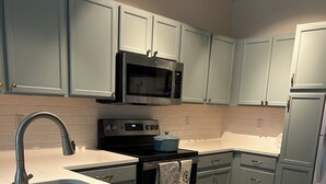 A modern kitchen with a stainless steel sink, a microwave, and a stove.
