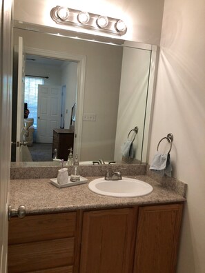 A bathroom with a white sink, a mirror, and a vanity with wooden cabinets. - Gated Community Condo 2.5 miles from the Ole Miss Campus (Oxford)