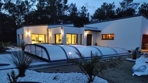 A modern house with a covered driveway, white exterior walls, and a well-maintained garden with white pebbles and plants. - CONTEMPORARY VILLA HEATED POOL CLOSE TO BEACH AND FOREST (Saint-Jean-de-Monts)