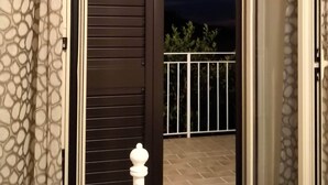 En balkong med utsikt över natthimlen, ett räcke och en dörr med en mönstrad gardin.