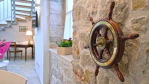 A ship's wheel mounted on a stone wall, a staircase, and a dining area with chairs and a table. - Frantoio House. Charming stone house in front of the dock (Betina)