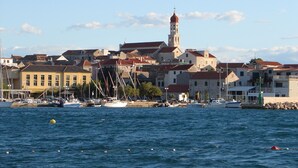 A coastal town with a prominent tower and a marina with boats. - Frantoio House. Charming stone house in front of the dock (Betina)