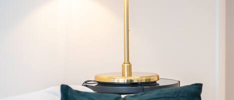 A modern lamp with a white shade and a gold base on a round table.