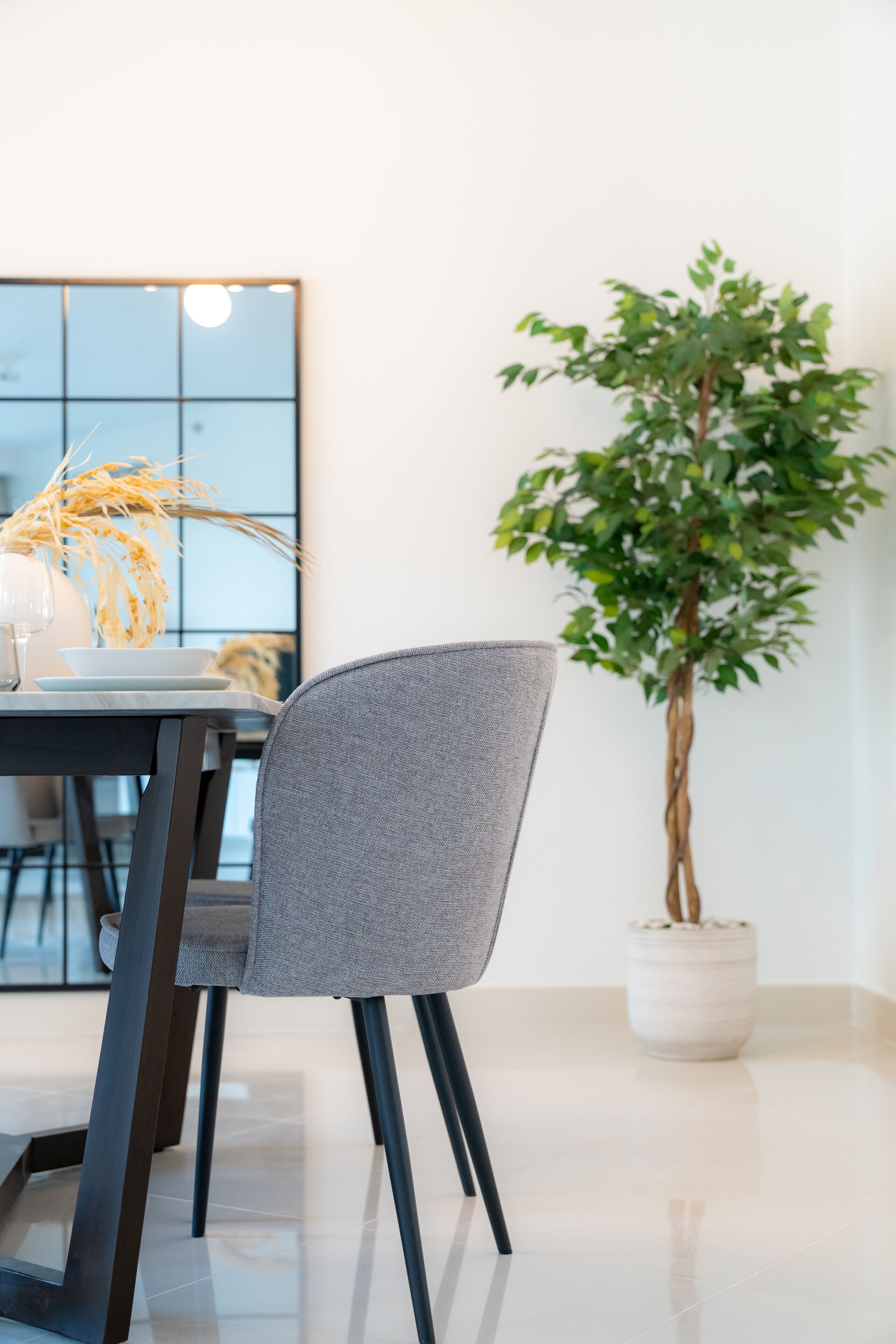 A modern dining area with a table, chairs, a potted plant, and a decorative vase.