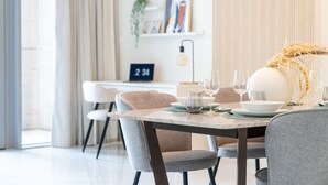 A modern dining area with a marble table, grey upholstered chairs, and a decorative vase. - HiGuests - Boulevard Crescent Tower 2 (Dubai)