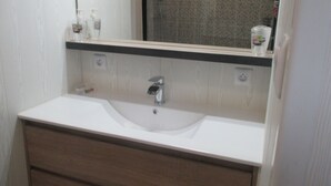 A bathroom with a white sink, wooden vanity, and a mirror above the sink. - Le Pijolin (Saint-Justin)