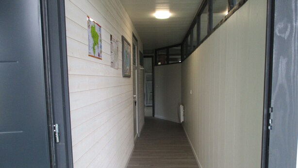 A narrow hallway with white walls and wooden flooring. There are doors on both sides and a light fixture on the ceiling. - Le Pijolin (Saint-Justin)
