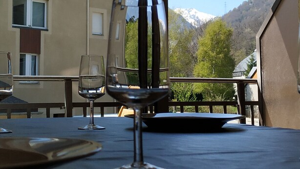 Une table avec un verre à vin et un verre à eau, donnant sur une montagne et un bâtiment.