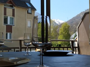 Una mesa con una copa de vino y una copa de agua, con vistas a una montaña y un edificio.