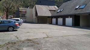 Un bâtiment avec un parking, un garage et une colline en arrière-plan.