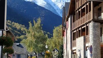 A street view with a mountain in the background, a building with a balcony, and parked cars.