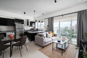 Un apartamento moderno con cocina, comedor y sala de estar, con un amplio ventanal que ofrece vistas a la ciudad.