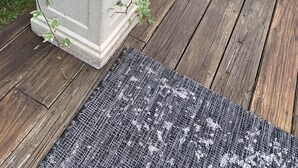 A concrete planter with a variety of plants on a wooden deck.