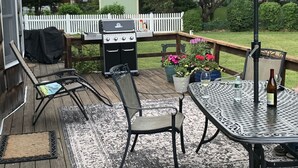 A deck with a grill, a table with chairs, and a large umbrella.