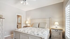 A bedroom with a bed, bedside tables, a ceiling fan, and a window with blinds.