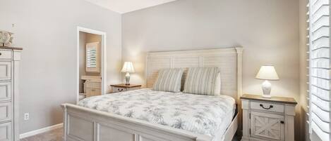 A bedroom with a bed, bedside tables, a ceiling fan, and a window with blinds.