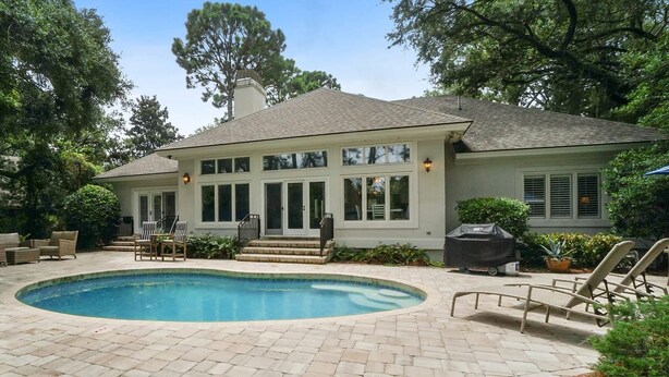 A house with a swimming pool, outdoor furniture, and a covered grill area.