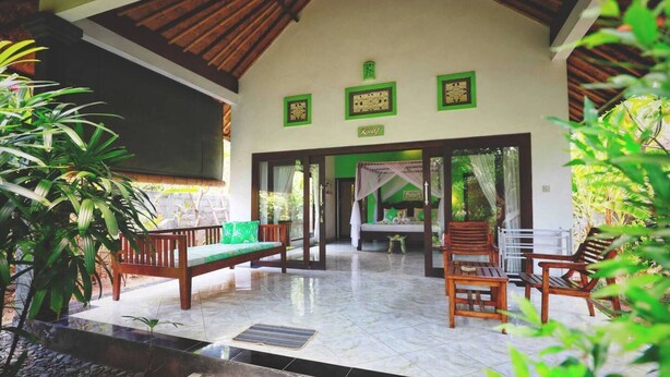 A spacious room with a high ceiling, a bed with a canopy, and a view of a lush garden. - Kirana Homestay - Leaf Bungalow (Karangasem)