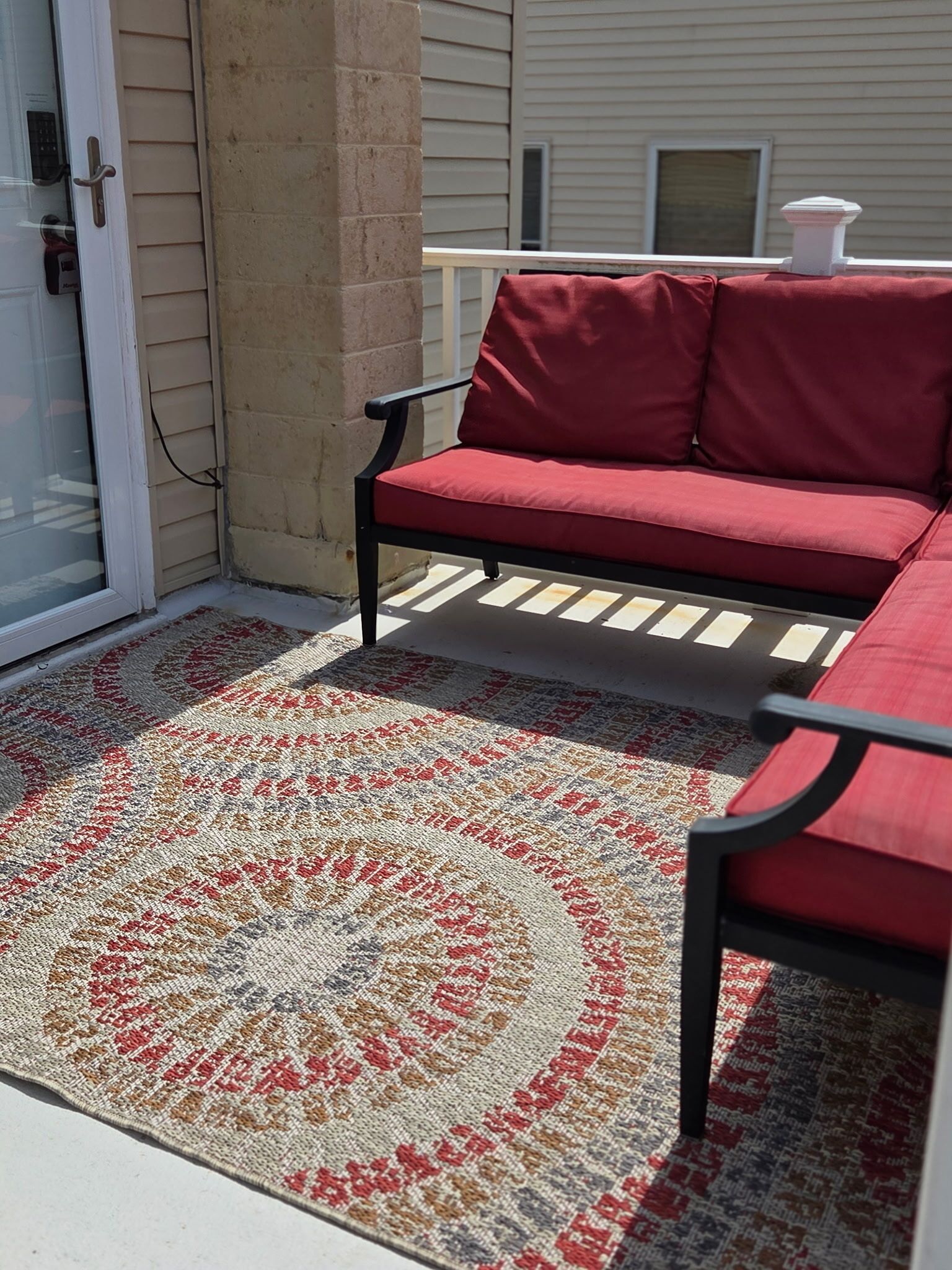 Een terras met een rode bank en een vloerkleed met een patroon.