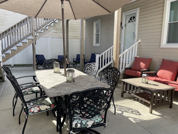 Une terrasse avec une table et des chaises, un canapé et un escalier menant à une maison.
