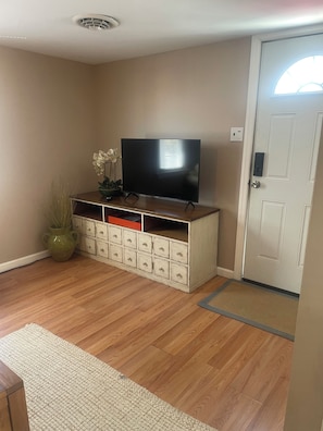 A room with a television on a wooden cabinet, a door with a keypad lock, and a small plant. -  Beach and Boardwalk 1.5  blocks. Lots of room w/ plaza and private porch.   (Wildwood)