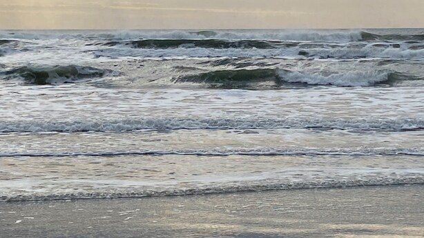 Una spiaggia con onde e cielo nuvoloso.