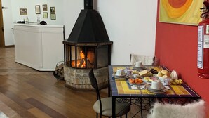A cozy room with a fireplace, a dining table set with plates and cups, and a red wall with a colorful painting. - Hotel Boutique SPA Lifestyle (RS)
