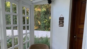 A room with a wicker chair, a patterned rug, and a wooden door. - Hotel Boutique SPA Lifestyle (RS)