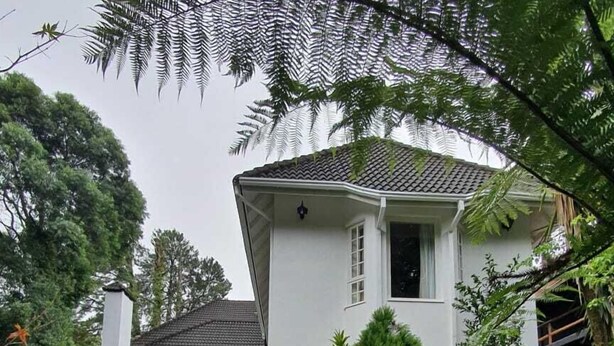 A two-story house with a white exterior, a tiled roof, and a well-maintained front yard with grass and shrubs. - Hotel Boutique SPA Lifestyle (RS)
