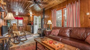 L’intérieur chaleureux d’un chalet avec un plafond en bois, un canapé en cuir, une table à manger et un coin cuisine.